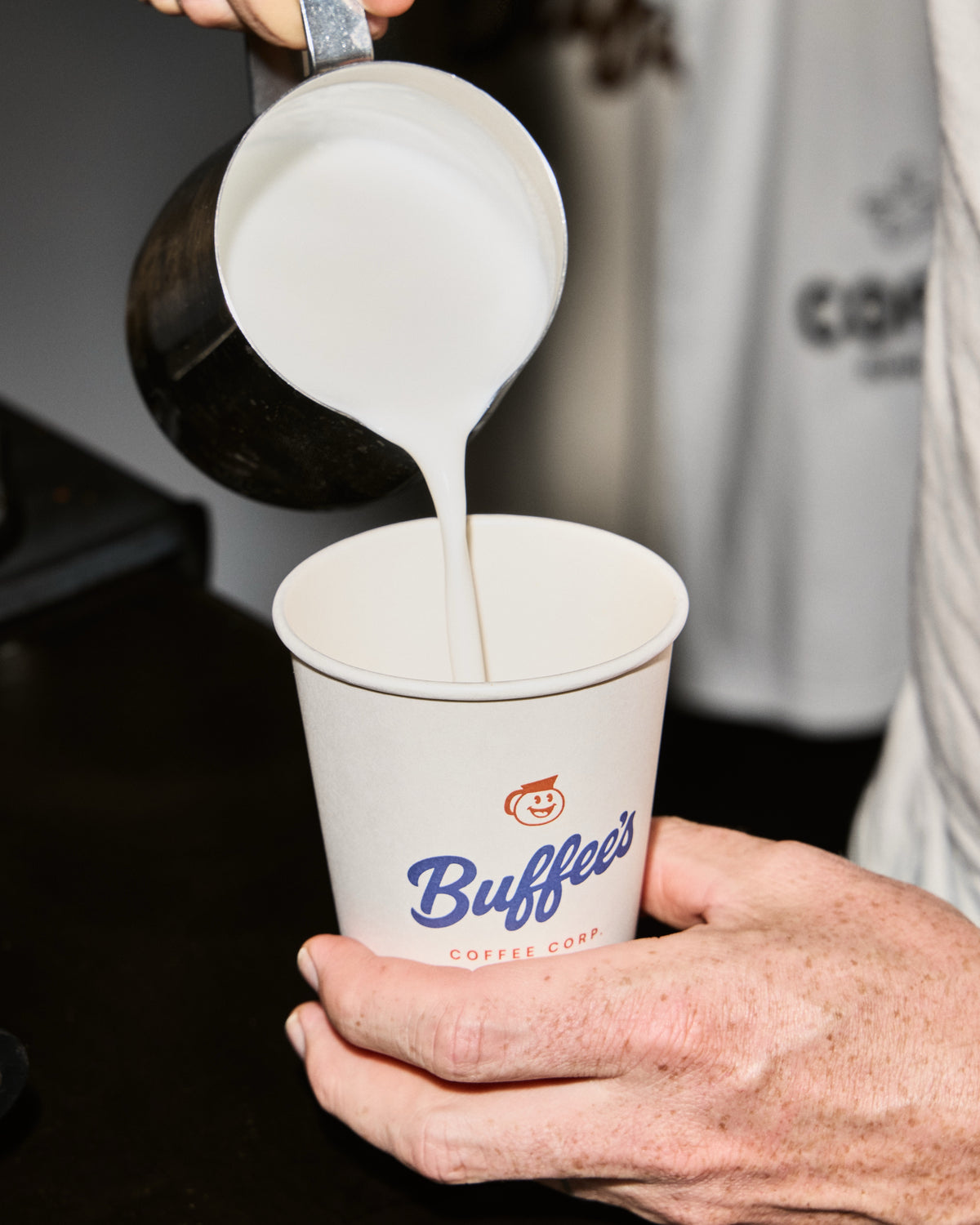 Barista pouring steamed milk into a cup